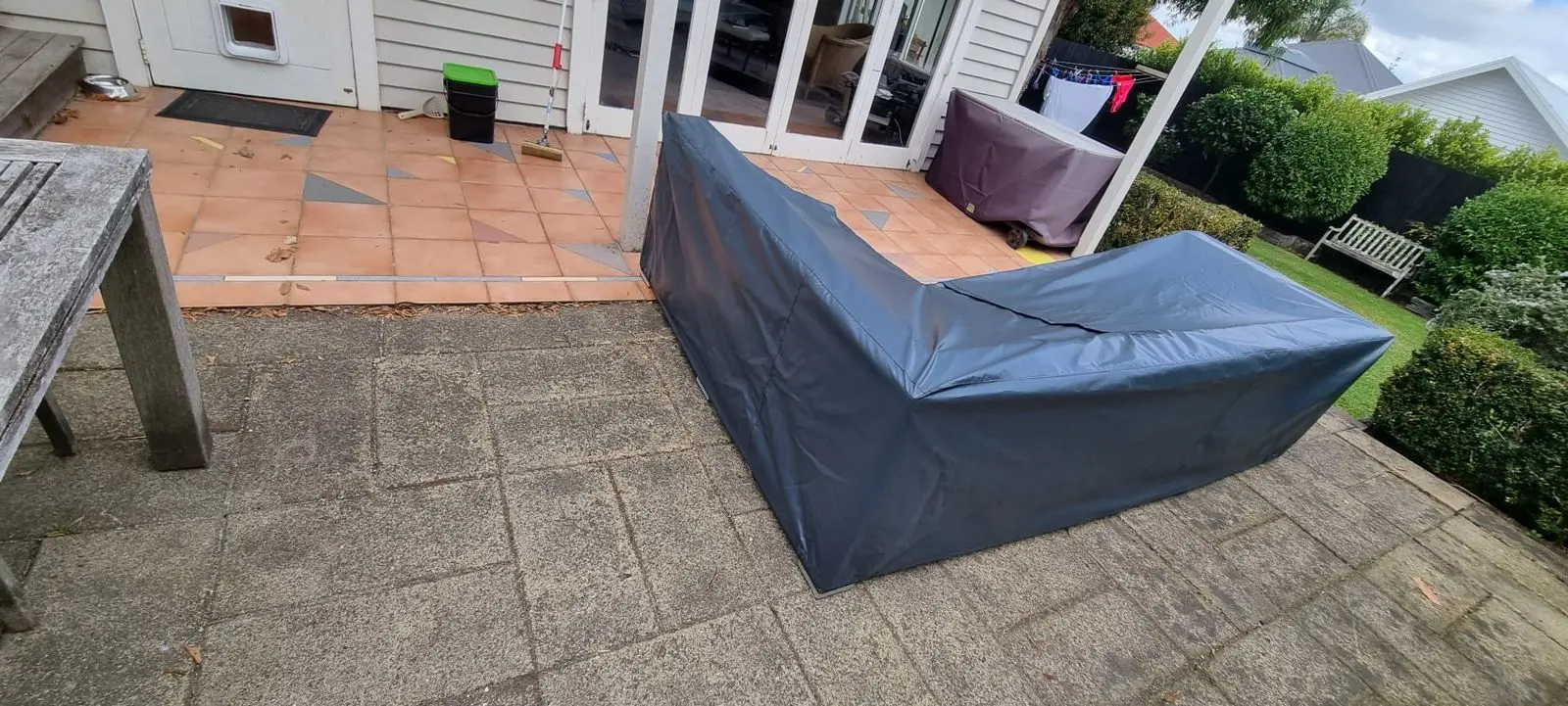 Grey fitted cover over corner outdoor furniture on a patio