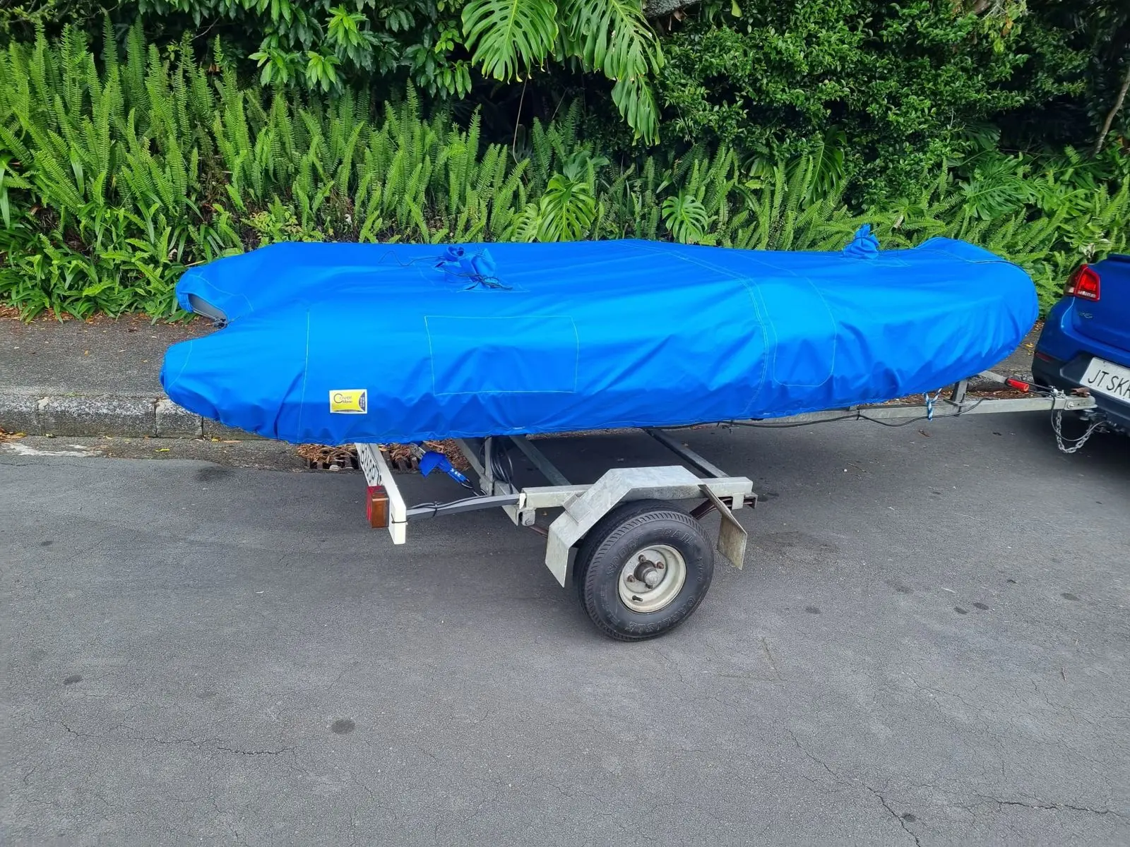 Blue fitted cover on an inflatable dinghy on its trailer