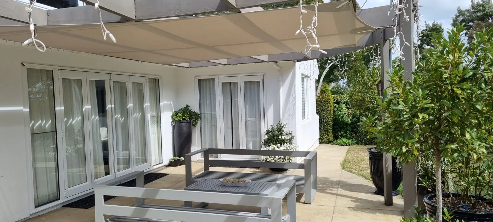 Cream shade sail installed over a house patio