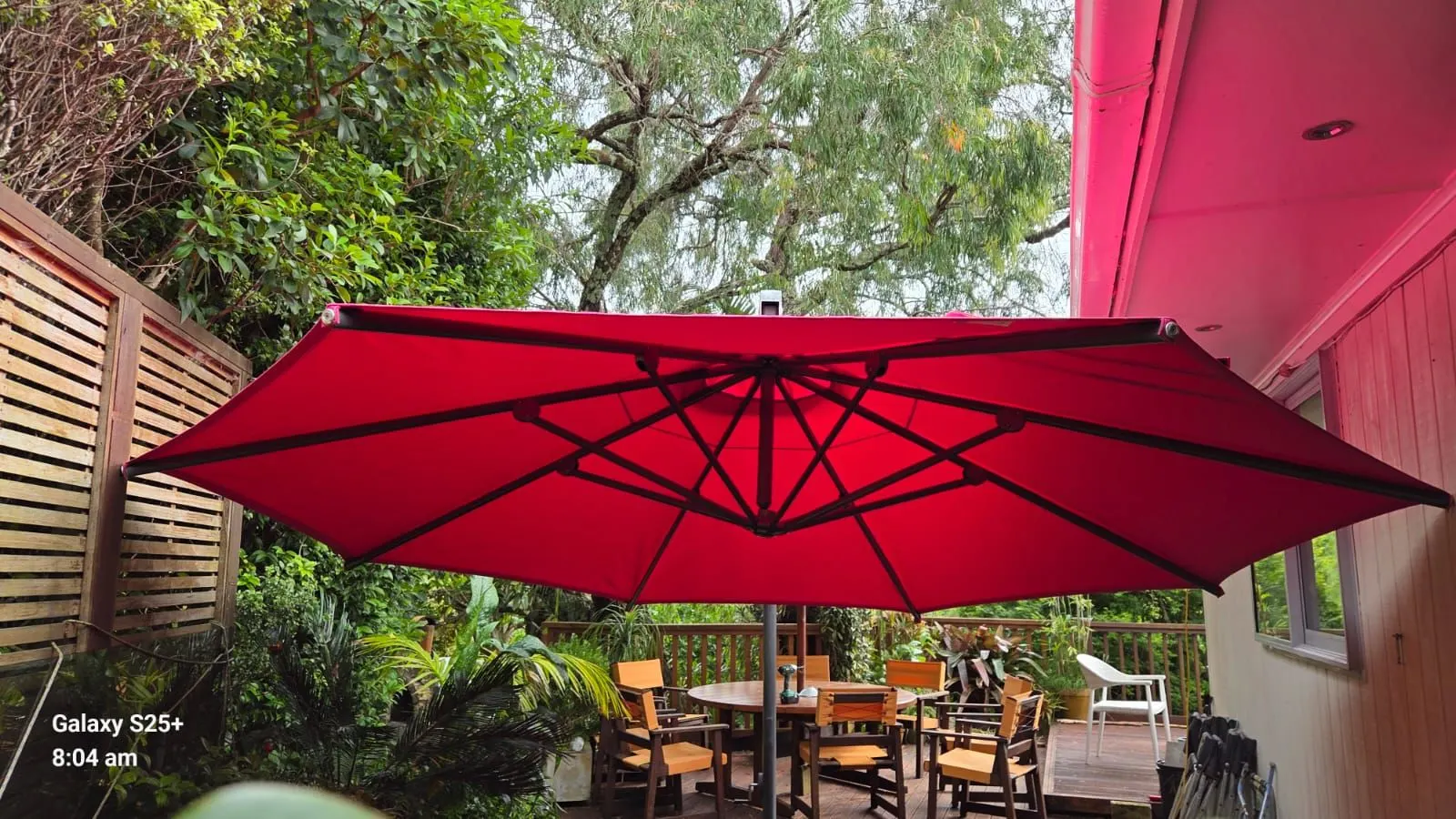 Large outdoor umbrella recovered in red acrylic canvas over an Auckland dining area